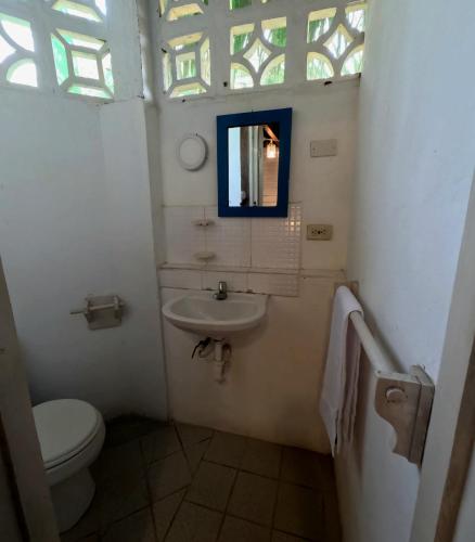 a bathroom with a sink and a toilet and a window at La Perla Hostel and Cabins in Las Tunas