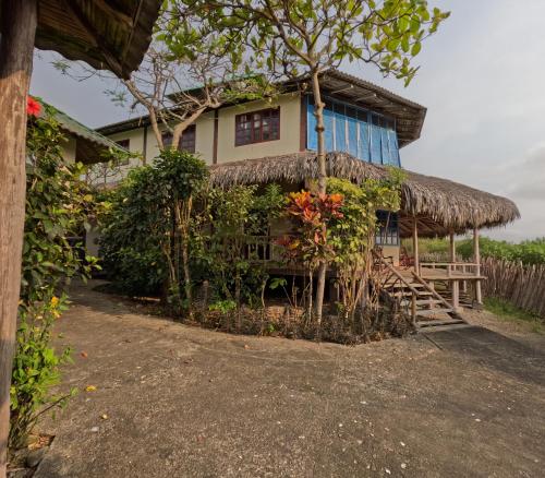 a house with a thatched roof at La Perla Hostel and Cabins in Las Tunas