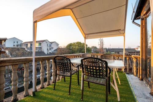 a table and chairs on a balcony with a view at Nanxun Luohua Old House Inn in Huzhou