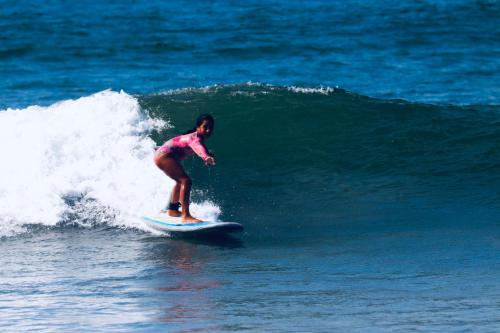 a woman riding a wave on a surfboard in the ocean at casaNorte paraíso norteño mirador de Ballenas in Canoas De Punta Sal