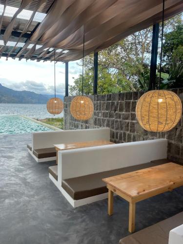 a restaurant with benches and tables and a view of the water at Zoola Resort San Pedro La Laguna in San Pedro La Laguna