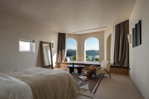 a bedroom with a bed and a table and two windows at Miyue Shenzhen Blue and White Holy Island Cliff Pool Hotel in Shenzhen