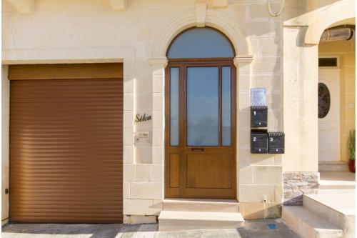 a building with a wooden door and a garage at Ta'Siku Gozitan villa Pool & hot tub - Happy Rentals in Il-Pergla