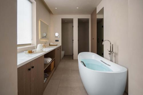 a bathroom with a large tub and two sinks at Miyue Shenzhen Blue and White Holy Island Cliff Pool Hotel in Shenzhen