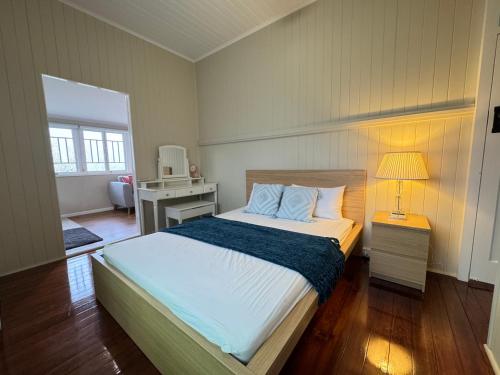 a bedroom with a bed and a desk with a lamp at Stylish & Bright 3-BDRS Family in Holland Park West in Brisbane