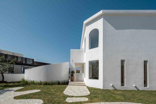 a white house with a pathway in front of it at Miyue Shenzhen Blue and White Holy Island Cliff Pool Hotel in Shenzhen