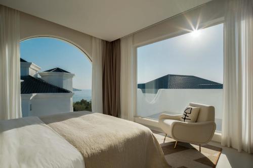 a bedroom with a bed and a chair and a large window at Miyue Shenzhen Blue and White Holy Island Cliff Pool Hotel in Shenzhen