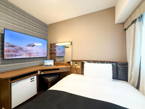 a hotel room with a bed and a desk with a monitor at APA Hotel Kagoshima Chuoekimae Nishiguchi in Kagoshima