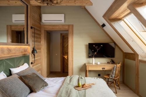 an attic bedroom with a bed and a desk at Villa La Roca Garden and Spa in Kościelisko
