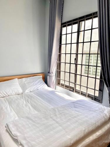 a bedroom with a white bed and a window at POTA Hotel & Apartment in Da Nang