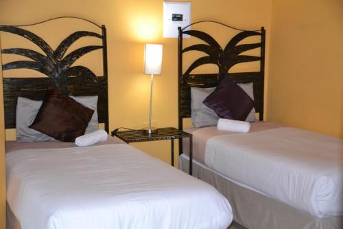 a hotel room with two beds and a lamp at Jump Street Chalets in Maun