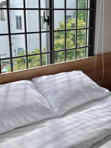 a bed with white sheets in front of a window at POTA Hotel & Apartment in Da Nang