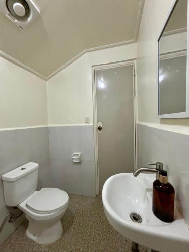a white bathroom with a toilet and a sink at Bundal Riverside in San Vicente