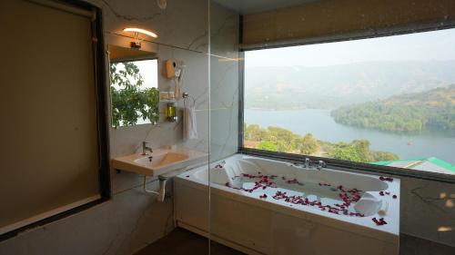 a bathroom with a tub and a sink and a window at Nisarga Lake Resort Tapola in Satara