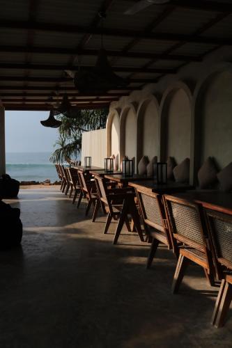 a row of wooden tables and chairs on the beach at Swell Shacks in Matara