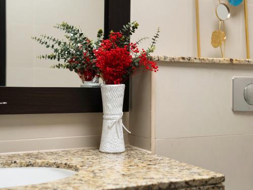a white vase with red flowers sitting on a counter at Luxury Apartments in Anantara Resort with Stunning Burj AlArab & Sea Views in Dubai