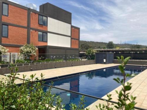 a building with a swimming pool in front of a building at CBD Apartments by the International in Wagga Wagga