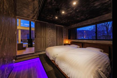 una camera da letto con un grande letto bianco con illuminazione viola di Tabinoteitaku Miyagi Zao a Zao