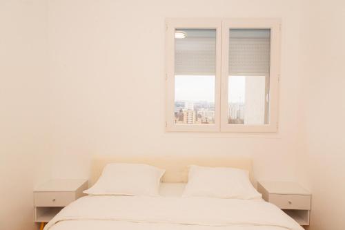 une chambre avec un lit blanc et une fenêtre dans l'établissement Appartement rénové situé aux portes de Paris, à Villeneuve-la-Garenne