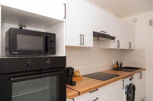 une petite cuisine avec un micro-ondes et une cuisinière dans l'établissement Appartement rénové situé aux portes de Paris, à Villeneuve-la-Garenne