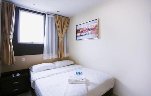 a bedroom with a white bed with a window at One Avenue Hotel in Petaling Jaya