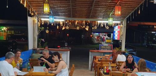 a group of people sitting at tables in a restaurant at Love Seeker House in Ko Lanta