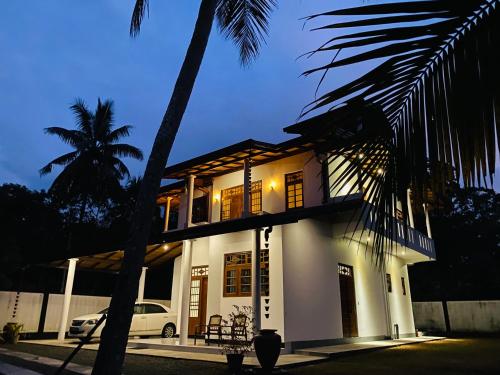 a white house with a palm tree in front of it at Coco Bay Villa in Galle