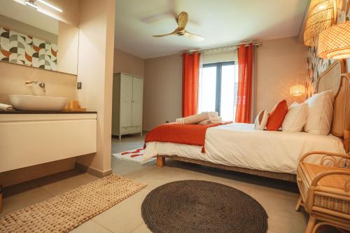 a bedroom with a bed and a bathroom with a sink at Villa Bo'M Bleue in Petite Île