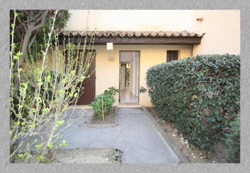 une maison avec une porte et une haie dans l'établissement LE LAVANDOU ST CLAIR STUDIO 300 m de la PLAGE parking, au Lavandou