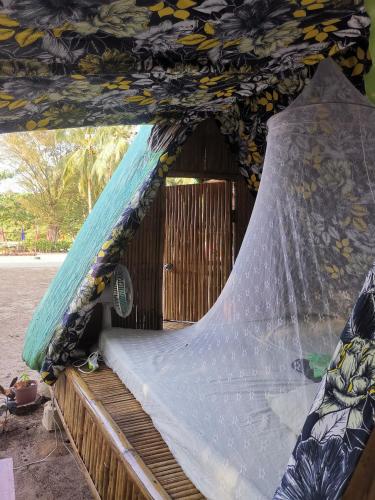 a bed with a net on top of it at El Nido Beach Camp in Manlalec