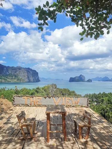 a picnic table and two chairs on a deck with a view of the water at El Nido Beach Camp in Manlalec
