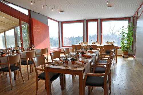 a dining room with tables and chairs and windows at EcoHotel L’Aubier in Montézillon