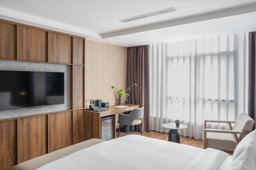 a hotel room with a bed and a tv and a desk at Kin Hotel Thai Van Lung in Ho Chi Minh City