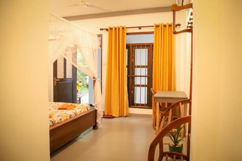 a bedroom with a bed and a table and yellow curtains at Kings Villa Mirissa in Mirissa