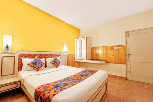 - une chambre avec un grand lit et un mur jaune dans l'établissement FabHotel JS Heritage, à Kodaikānāl