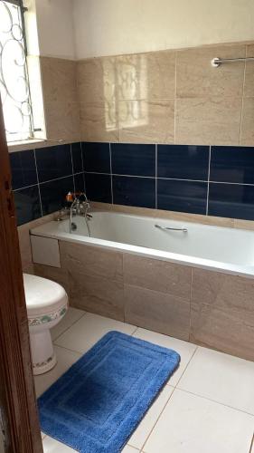 a bathroom with a tub and a toilet and a blue rug at Bonsai Villa in Nairobi