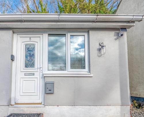 a white house with a door and a window at Butland Cottage in Pembroke