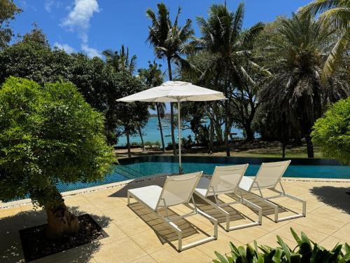 Villa exceptionnelle en bord de mer في ترو دو دوس: مجموعة كراسي ومظلة بجانب مسبح