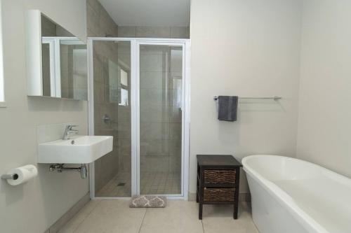 a bathroom with a shower and a tub and a sink at Just Beachy Bellamare Apartment in Summerstrand
