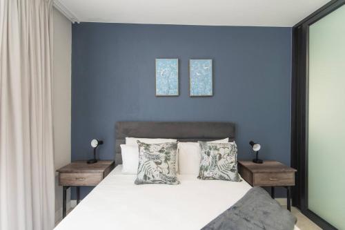 a bedroom with blue walls and a bed with pillows at Just Beachy Bellamare Apartment in Summerstrand