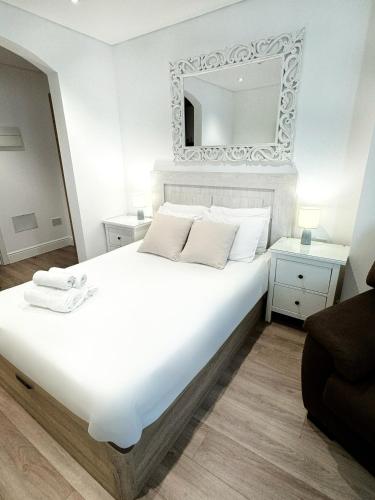 a bedroom with a large white bed with a mirror at Delightful City Centre Studio Clarendon Apartment - Grand Central House in Gibraltar