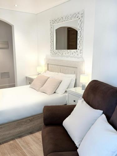 a bedroom with a bed with a mirror and a couch at Delightful City Centre Studio Clarendon Apartment - Grand Central House in Gibraltar