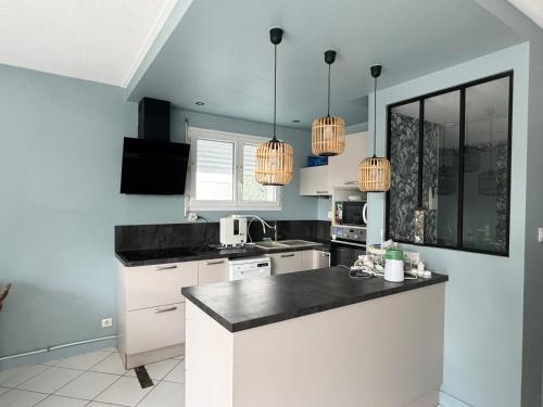 une cuisine avec des armoires blanches et des comptoirs noirs dans l'établissement Rompsay, à La Rochelle