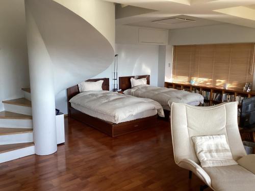 a bedroom with two beds and a staircase and a chair at 貸別荘しおのか in Tokashiku
