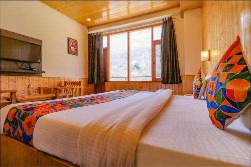 a bedroom with a large bed and a window at Hotel 17 Miles Stone, Manali By Shivaneel Hospitality in Manāli
