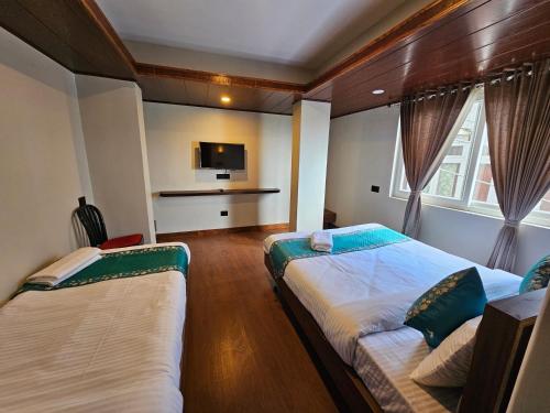 a hotel room with two beds and a tv at Hotel Tara Palace Darjeeling in Darjeeling