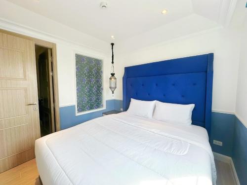 a bed with a blue headboard in a bedroom at Jomtien Beach, Pattaya - Seven Seas Côte d'Azur in Na Jomtien