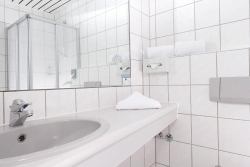 a white bathroom with a sink and a mirror at Good Morning + Bad Oldesloe in Bad Oldesloe