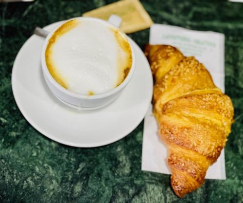 a plate with a cup of coffee and a croissant at La casa dell’artista di Vittorio Vertone in Pietragalla