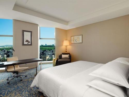 a hotel room with a bed and a desk and a window at Sheraton Changchun Jingyuetan Hotel in Changchun